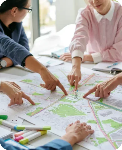 Pessoas em volta de uma mesa contendo um mapa, discutindo projetos.